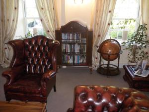 a living room with a leather couch and a book shelf at Longfrie Inn in St Saviour Guernsey