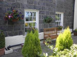 un banco frente a un edificio de ladrillo con ventanas en Longfrie Inn en St Saviour Guernsey