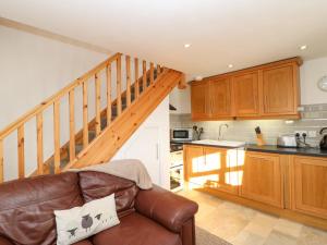 uma sala de estar com um sofá e uma cozinha em Drover's Cottage em Wolsingham