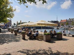 grupa ludzi siedzących przy stolikach pod parasolem w obiekcie The Walnut Tree w mieście Hellevoetsluis