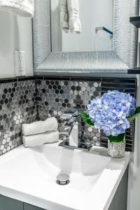 a bathroom sink with a vase of blue flowers on it at NB Urban Luxury Suites in Toronto +158 photos