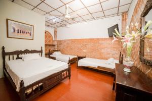 a bedroom with two beds and a brick wall at Hotel San Andres Mompox in Mompos