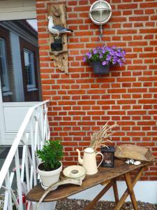 a table next to a brick wall with flowers and plants at Ferielejlighed Rubjerg Præstegård in Løkken