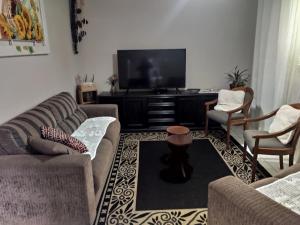 a living room with two couches and a flat screen tv at Casa da Daiana na Praia da Cal Torres in Torres