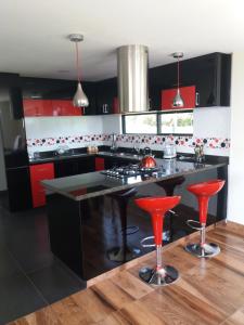 una cocina con armarios rojos y una isla negra con taburetes rojos en Sierra Morena, en Cogua