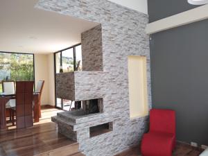 a living room with a stone fireplace with a red chair at Sierra Morena in Cogua