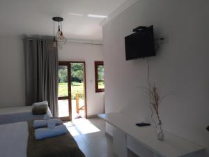 a living room with a couch and a tv on the wall at Chalé Águas Claras in Capitólio