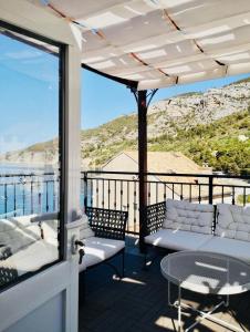 a balcony with white furniture and a view of the ocean at Komiza Provita Guesthouse in Komiža