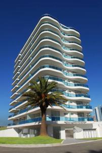 a tall building with a palm tree in front of it at Categoría, excelente ubicación y full amenities! in Punta del Este