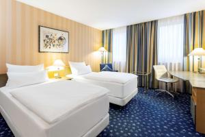 Pokój hotelowy z 2 łóżkami i biurkiem w obiekcie NH Danube City w Wiedniu