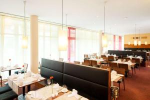 a dining room with tables and chairs and windows at NH München Ost Conference Center in Munich