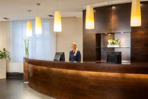 a woman sitting at a reception counter in a hotel lobby at NH Düsseldorf Königsallee in Düsseldorf