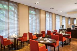 إن إتش دوسلدورف كونيساله في دوسلدورف: مطعم به طاولات وكراسي حمراء ونوافذ