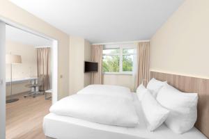 a bedroom with a white bed with white pillows at NH Fürth Nürnberg in Fürth