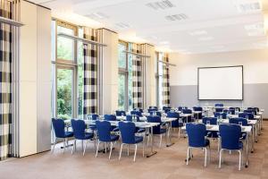 una sala de conferencias con mesas, sillas y una pizarra en NH Frankfurt Niederrad en Frankfurt