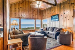 a living room with couches and a table and windows at Coastal Serenity in Lincoln City
