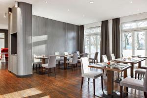 a dining room with tables and chairs and windows at NH Collection Hamburg City in Hamburg