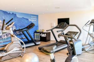 a gym with cardio machines and a wall mural at NH Leipzig Messe in Leipzig