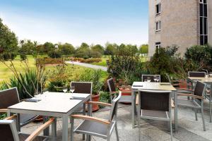 eine Reihe von Tischen und Stühlen auf einer Terrasse in der Unterkunft NH Leipzig Messe in Leipzig