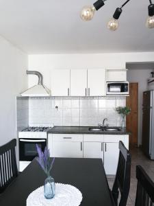 a kitchen with white cabinets and a table with a vase at DEPARTAMENTOS Las Araucarias- 2 a 5 personas con estacionamiento in Neuquén