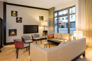 a living room with a couch and chairs and a tv at NH Collection Nürnberg City in Nürnberg