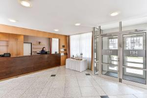 a lobby with a reception desk and a woman in a room at NH München City Süd in Munich