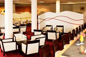 a restaurant with tables and chairs and a wall at NH Oberhausen in Oberhausen +28 photos