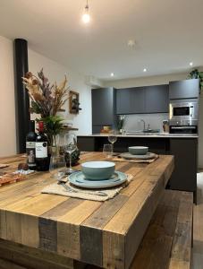 a kitchen with a wooden table with plates and wine glasses at EXCLUSIVE and MODERN - Bradford City Centre- 85" Cinema TV in Bradford