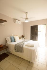 a bedroom with a bed with white sheets and blue pillows at Apartamento Guaratuba in Guaratuba