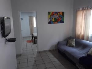 sala de estar con sofá y TV en Aconchego 3 dorms, piscina, churrasq em Condomínio Fechado, en Boicucanga