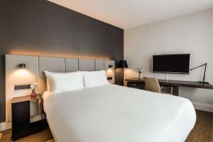 ein Hotelzimmer mit einem großen Bett und einem TV in der Unterkunft NH Amsterdam Caransa in Amsterdam