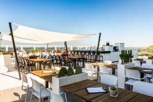 an outdoor patio with tables and chairs and the ocean at NH Atlantic Den Haag in The Hague