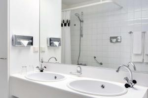 een witte badkamer met 2 wastafels en een spiegel bij NH Zandvoort Hotel in Zandvoort