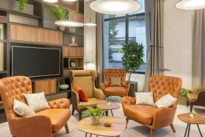 a waiting room with chairs and a flat screen tv at NH Essen in Essen