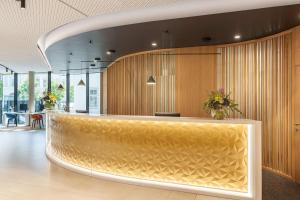 a lobby with a large gold reception counter at NH Graz City in Graz