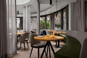 ブリュッセルにあるNH ブリュッセル EU ベルレモンのテーブルと椅子、大きな窓のあるレストラン