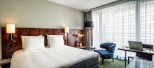 a hotel room with a bed and a desk and a laptop at NH Brussels EU Berlaymont in Brussels