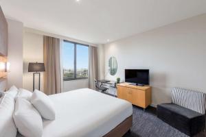 a hotel room with a large bed and a television at Radisson On Flagstaff Gardens Melbourne in Melbourne