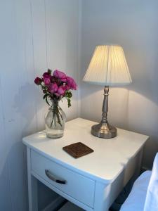 a table with a lamp and a vase of flowers on it at Ohariu Farm Cottage in Johnsonville