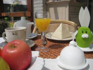 uma mesa com uma maçã e um copo de sumo de laranja em B&B Huize Bex em Overpelt