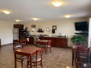 a restaurant with tables and chairs and a kitchen at SureStay Plus Hotel by Best Western Hardisty in Hardisty