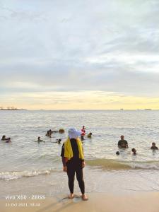 una persona in piedi sulla spiaggia con un gruppo di persone in acqua di Marose Gold Coast Morib a Morib