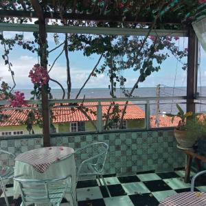 patio ze stołem i krzesłami oraz widokiem na ocean w obiekcie Pousada Tiriri Guesthouse w mieście Barra do Camaragibe