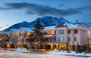 a hotel with a snow covered mountain in the background at Red Carpet Inn in Banff