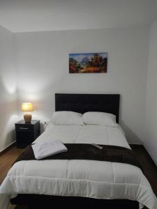 a bedroom with a large bed with a painting on the wall at Hospedaje El Girasol TABABELA in Quito