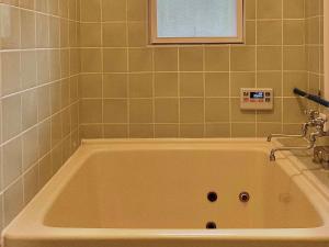 a bath tub in a bathroom with green tiles at Gallery HARA and guest house in Hara
