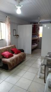 - un salon avec un canapé et des oreillers rouges dans l'établissement Kitnet para Temporada no Litoral SP, à Praia Grande