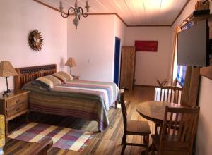 ein Schlafzimmer mit einem Bett, einem Tisch und einem sidx sidx sidx in der Unterkunft Tiradentes Pousada Ramalhete in Tiradentes