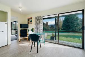 a kitchen and living room with a table and a large window at Glendhu Station Cottage - Glendhu Bay Holiday Home in Glendhu