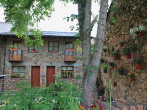 a stone house with potted plants and a tree at Casa rural El Trubio in Vigo de Sanabria
